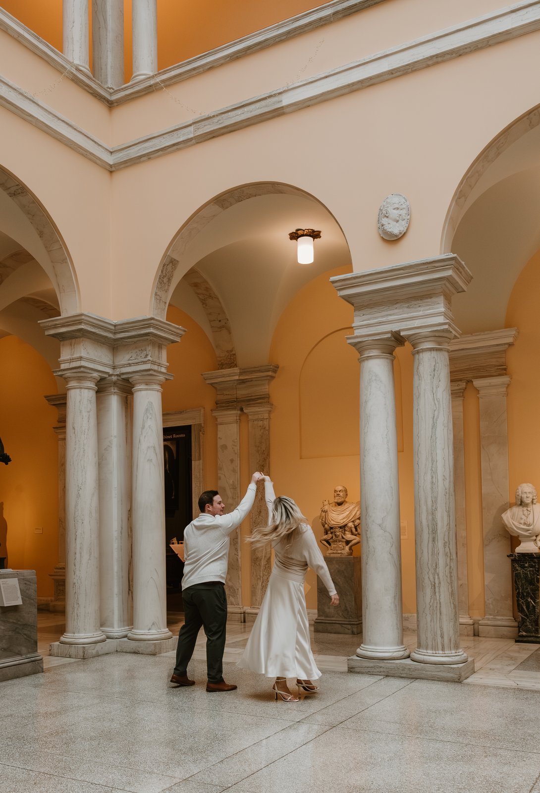 Michael twirling Karley beneath marble columns
