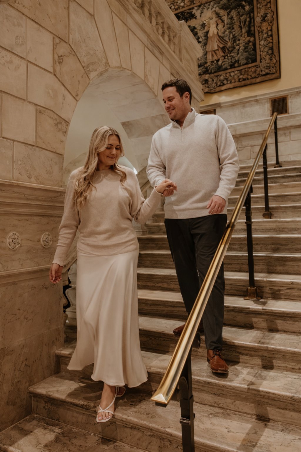 Michael leading Karley down a grand marble staircase